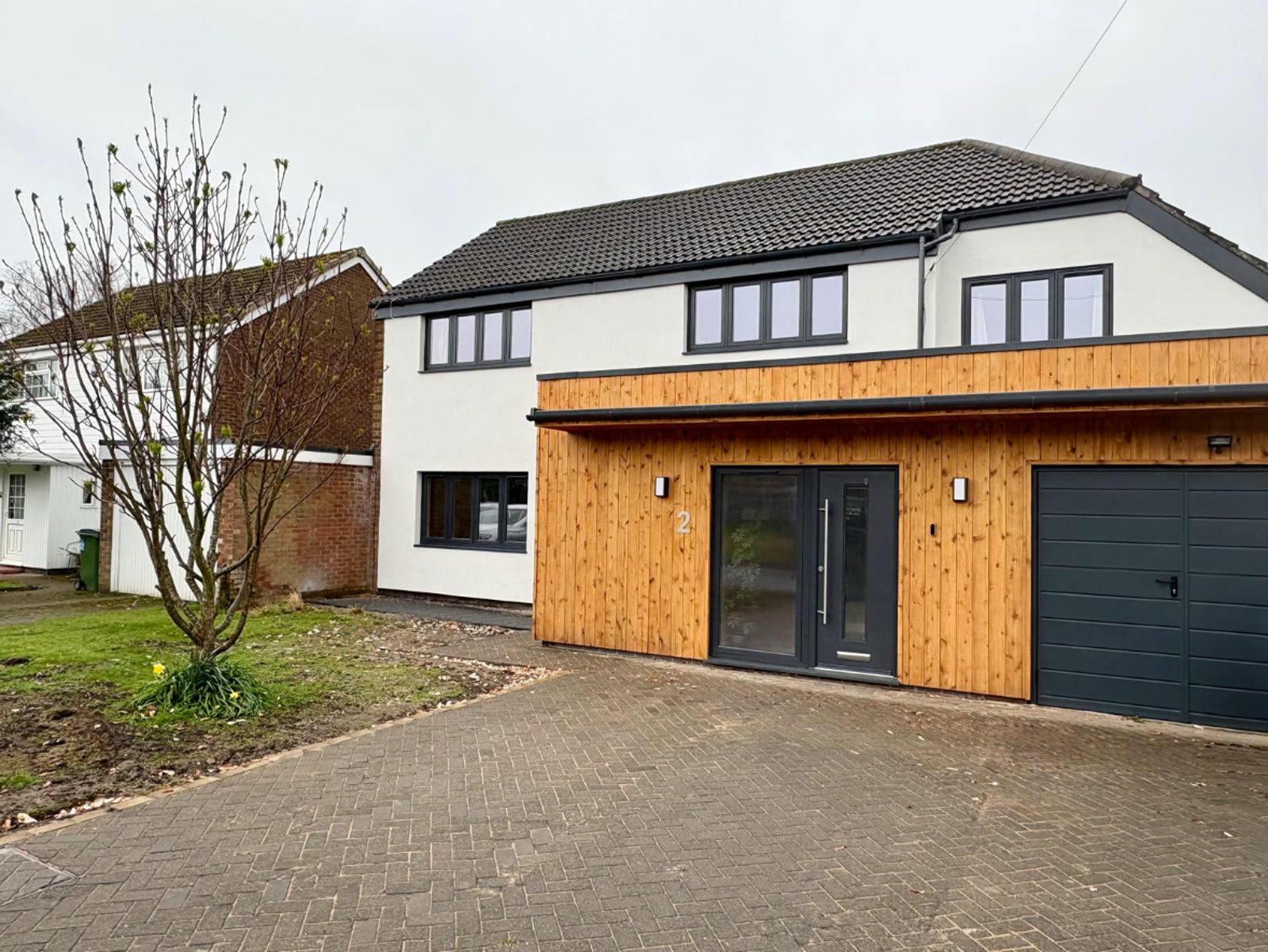 The finished house in white silicone render with timber cladding